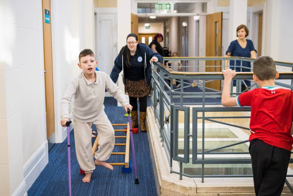 Child on crutches stepping through a ladder on the floor