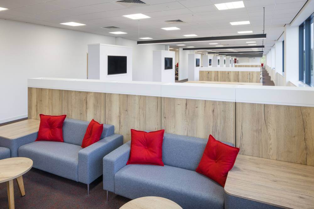 Grey, two-seater sofa in an office with red cushions