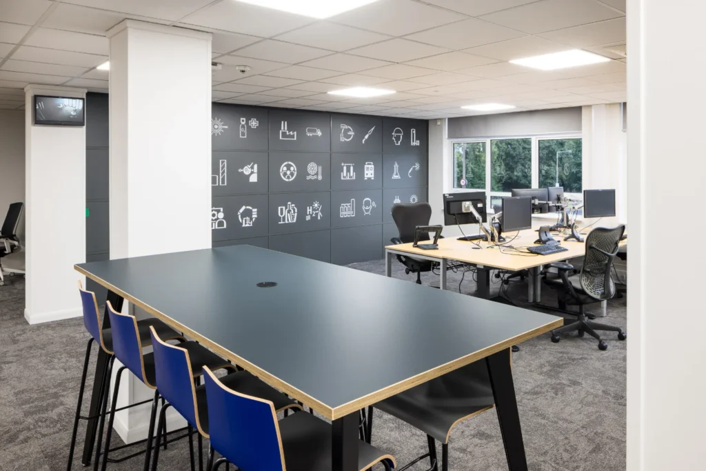 A dark office space with logos depicting different sectors on a partition wall