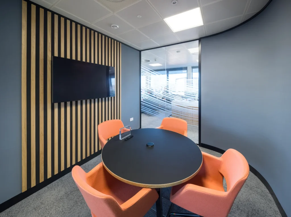modern meeting room with TV, glass partitions, and office seating