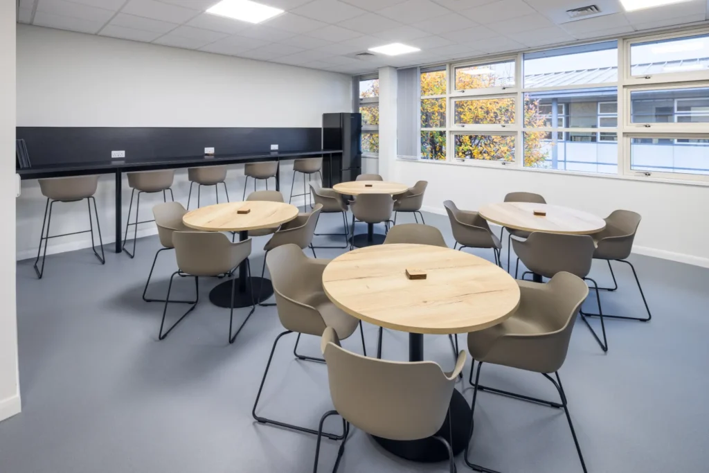 Modern office fit out breakout and dining area with café-style seating, high bar workspace, contemporary lighting, and collaborative staff kitchen environment.